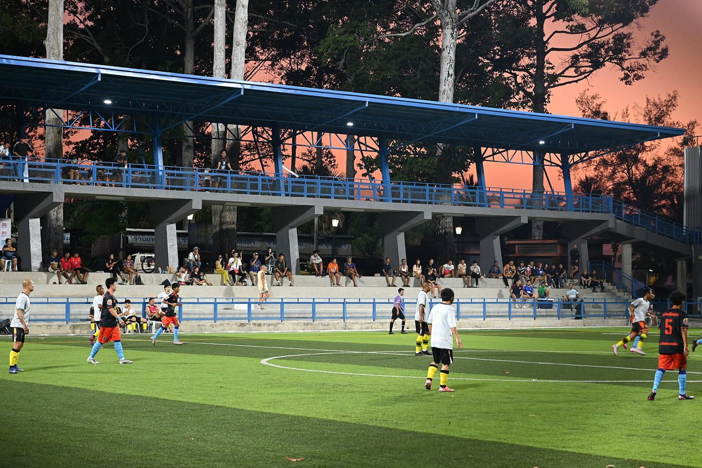 Photograph of a community sports pitch under evening floodlights.
